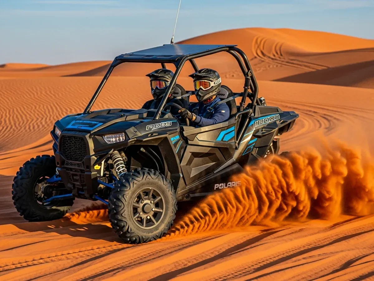 Two riders in a black Polaris RZR 1000 dune buggy throwing sand on an Al Khatim dune near Abu Dhabi