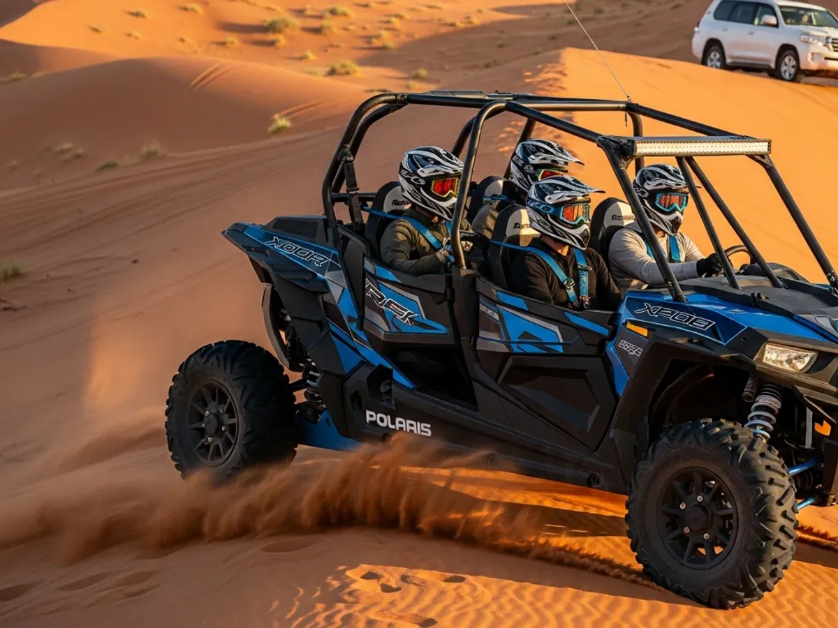 Four helmeted riders in a blue 4-seater Polaris RZR 1000 dune buggy driving across orange dunes