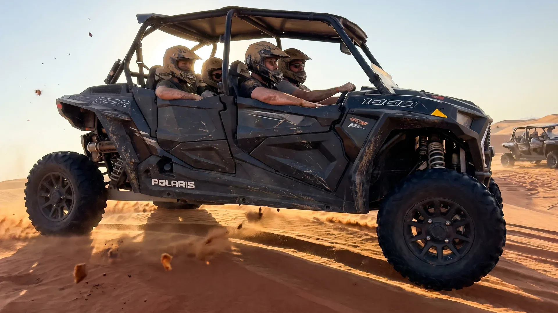 Side view of a Polaris RZR 1000 buggy carrying a group through the Abu Dhabi desert