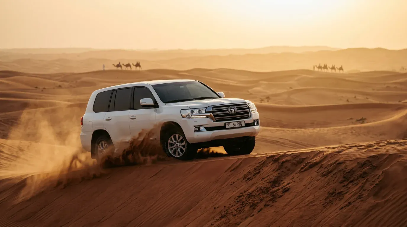 Private white Land Cruiser 4x4 driving over a dune ridge on a morning desert safari