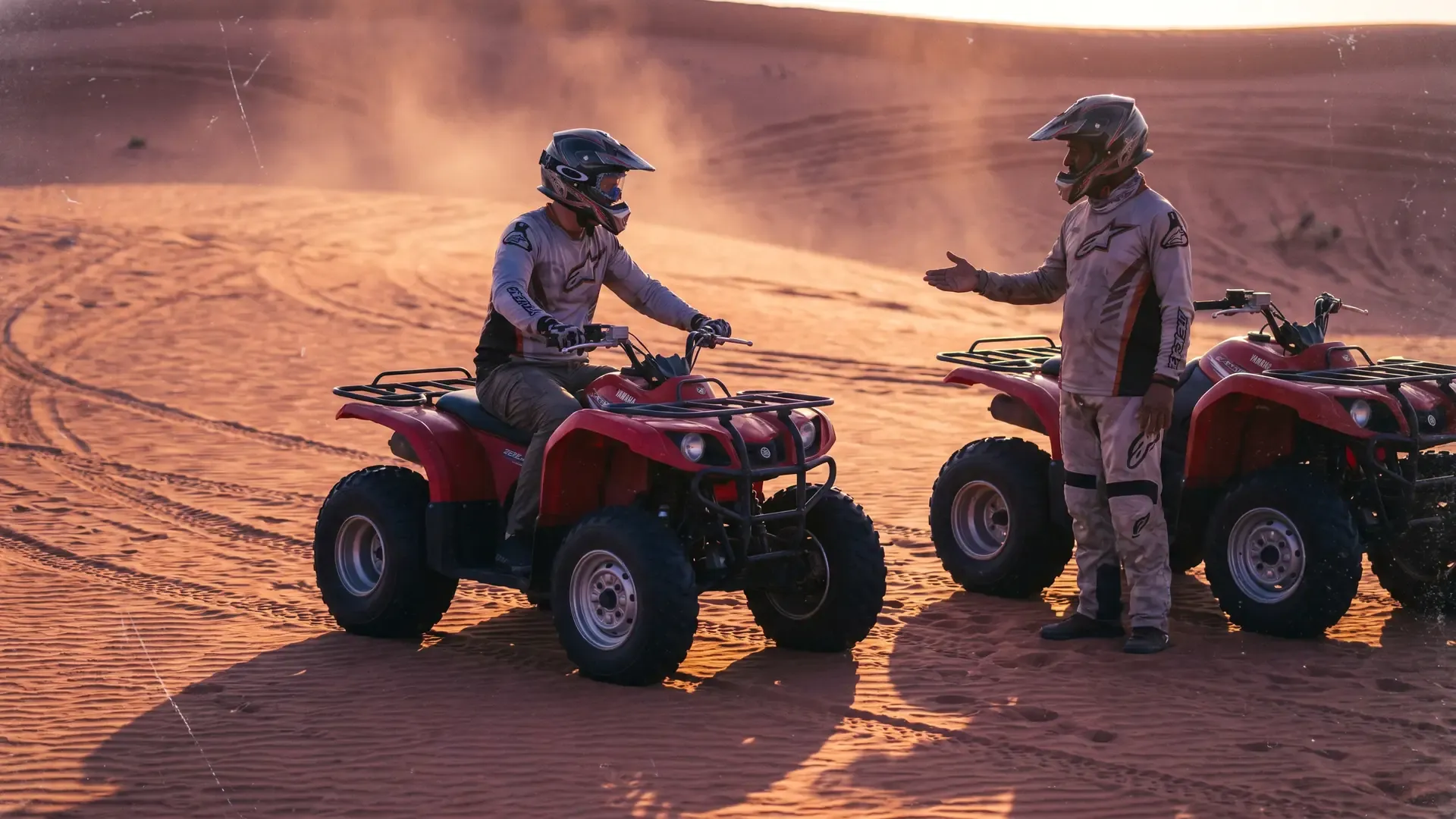 Guide giving a safety briefing to a quad bike rider beside a second quad on the sand