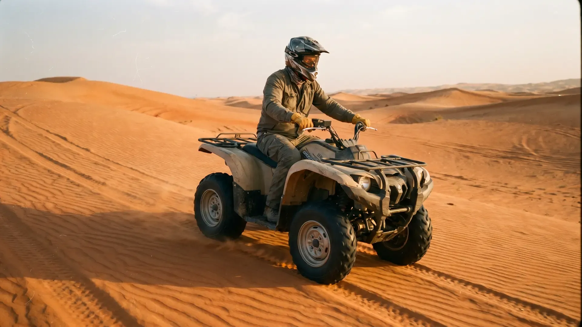 Quad bike rider in a helmet crossing a flat sand stretch of Al Khatim Desert